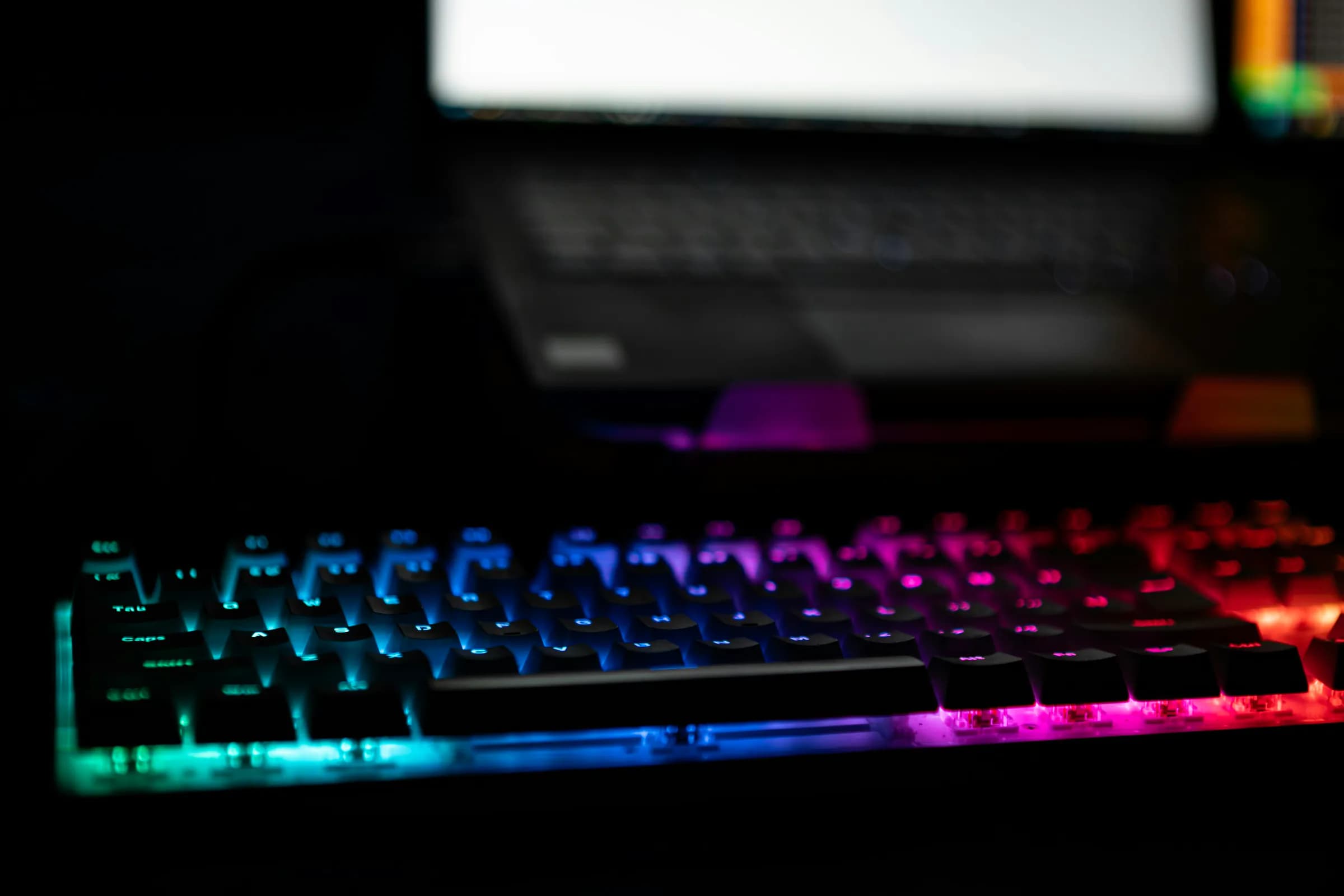 A mechanical keyboard with rainbow backlighting in the dark.