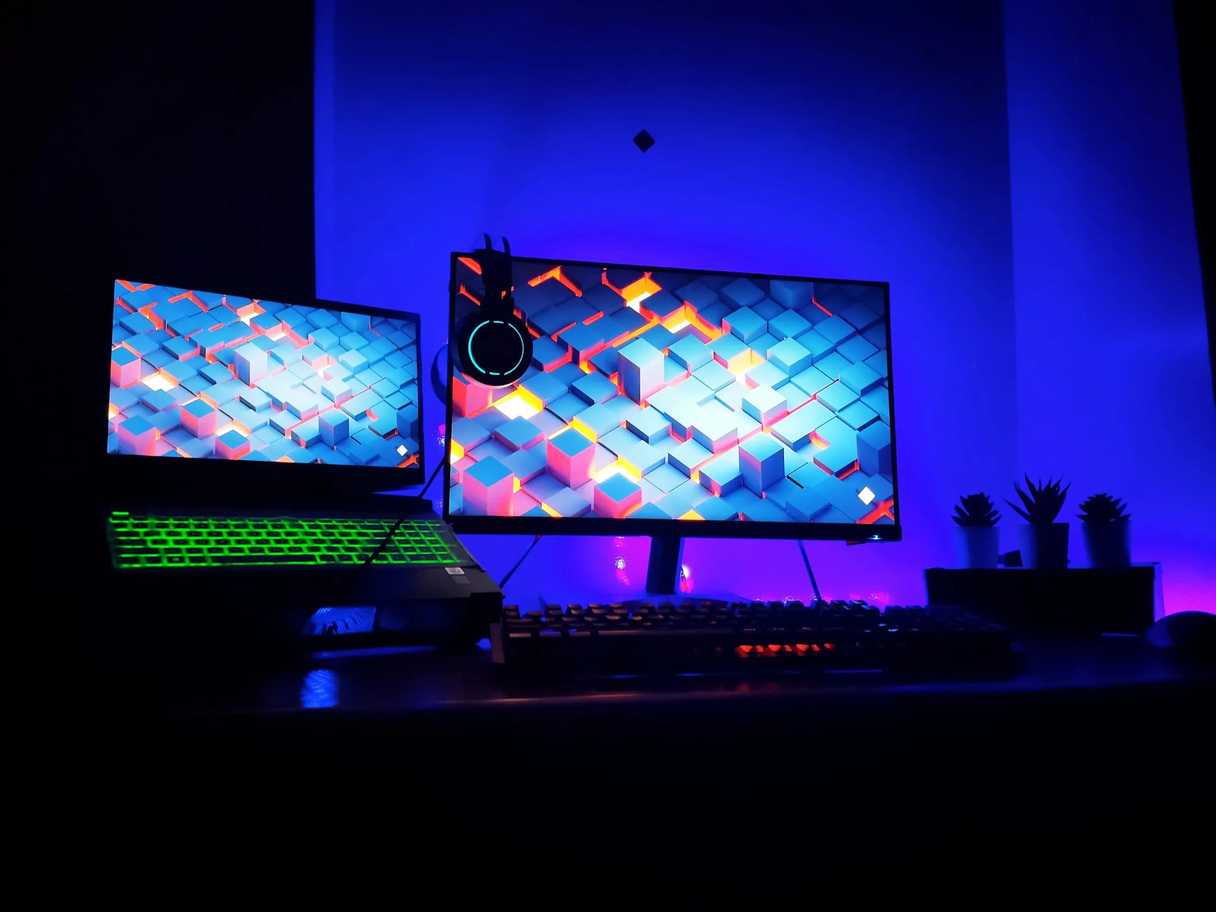A gaming setup with two monitors in deep blue and violet light.